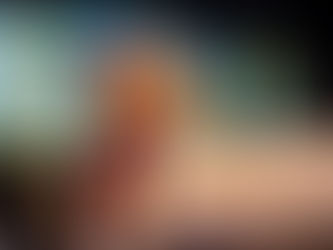 A young actor in lion makeup sits looking into the distance in front of a painted landscape, while five actors in colorful African-print dresses stand in the background