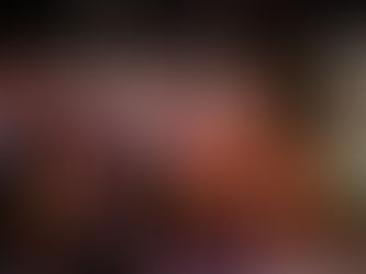 A large group of newsies stand with a fist in the air, lit dramatically in yellow and pink.