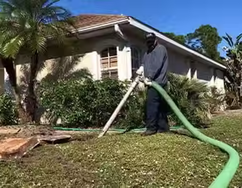 Technician pumping a residential septic tank with a vacuum truck