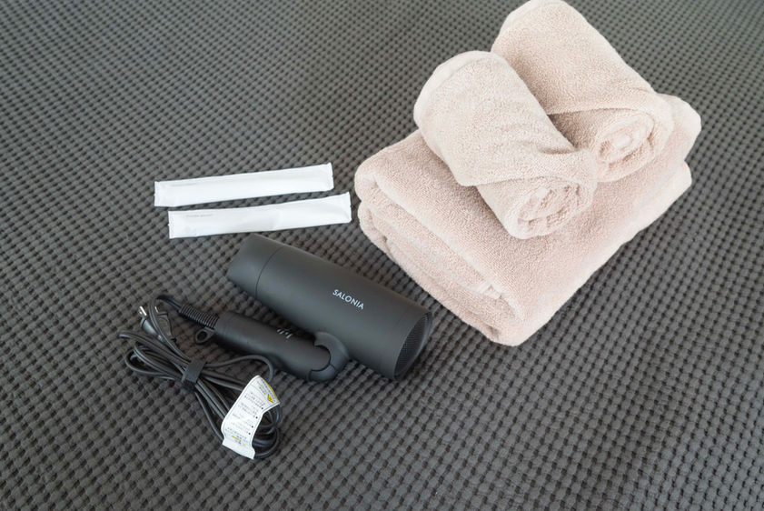 Laundry and vanity area with washer-dryer combo, face and bath towels, toothbrushes, and hair dryer in a Japanese guesthouse