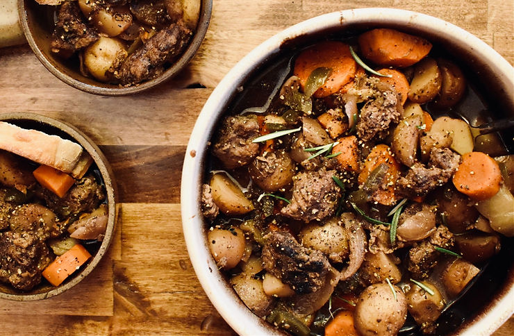 Perfect for a cozy meal -- Hearty bison stew with tender chunks of bison, carrots, and potatoes, garnished with fresh rosemary, served alongside crusty bread.