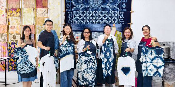 Hand-dyed indigo t-shirts held up by a tour group at the end of a session in Sathorn, Bangkok