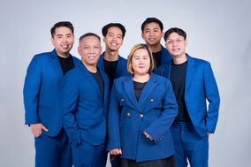Team of 6 professionals in blue suits on blue backdrop at LPS Headshot Studio Bangkok