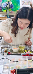 Guests setting dried flowers into glass vessels during a candle workshop in Bangkok