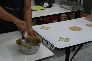 Participants applying stencil and rice paste resist at GIGIPAYNE Studio in Bangkok