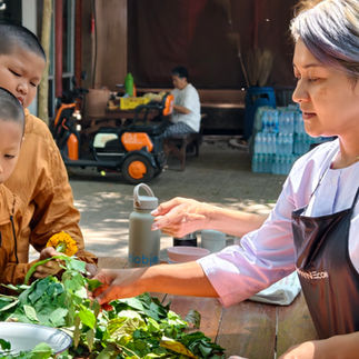 Gigi Payne guiding young student through leaf selection during eco-print craft session at Wat Sukato monastery Thailand