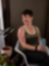 photo of a brunette woman with short hair, wearing a green tanktop that says "Green Queen." She's smiling & holding a coffee