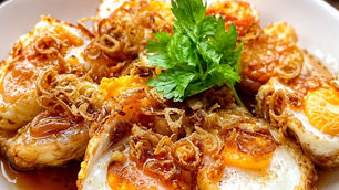 A plate of crispy Kai Look Koei (Thai Son-in-Law Eggs) topped with sweet tamarind sauce, fried shallots, and dried chilies.