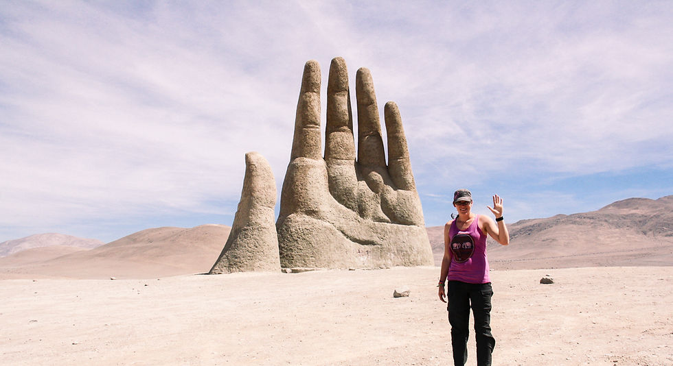 Girl standing in the desert with a big rock hand behind