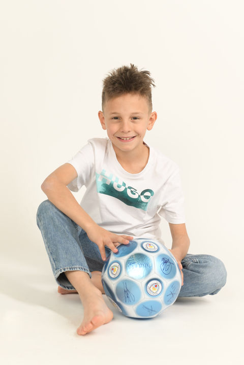 Lächelnder Junge mit Fußball bei einem persönlichen Kinderfotoshooting in Wiener Neustadt