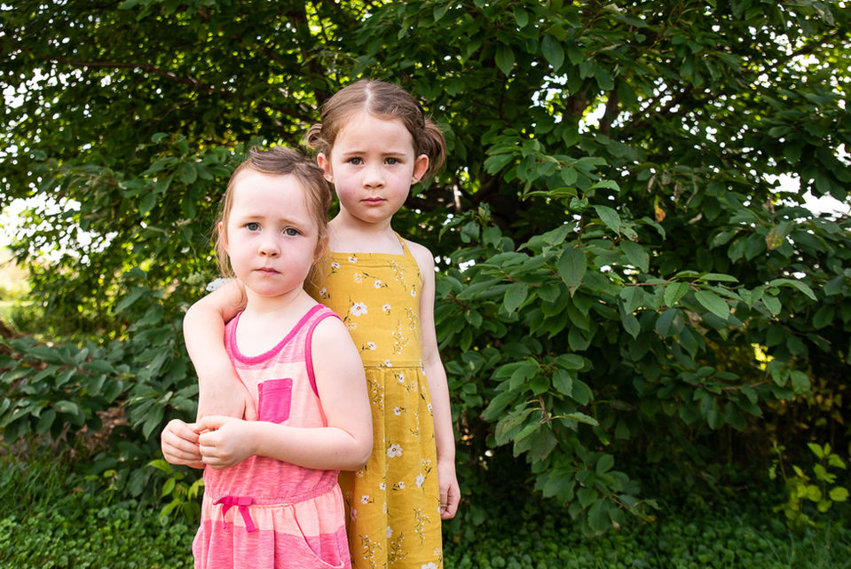 Photo of two sisters cuddling on the farm