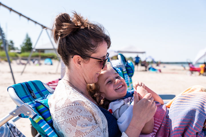 Mom cuddles son during family documentary photos at Sauble Beach