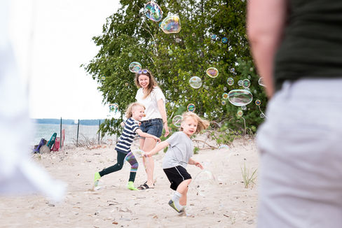 Mom and sons play with bubbles on a Kincardine Beach during an extended family photoshoot