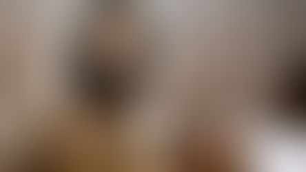 Two men in robes read an ancient scroll in a softly lit room. Their expressions are focused and respectful, creating a serene atmosphere.