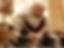 A person in historical attire writes with a quill at a wooden desk. Blurred background. Warm colors create an ancient, thoughtful ambiance.