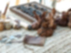 Coins, scrolls, and leather pouches on a woven mat with an abacus in background. Earth tones dominate the rustic scene.