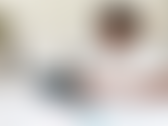 Black teen smiling at computer with headphones and curly hair