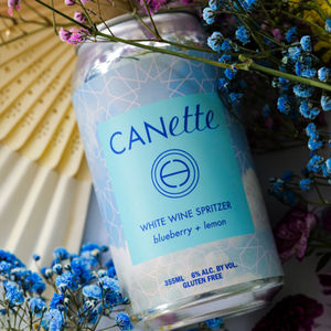 Canette white wine spritzer surrounded by flowers.