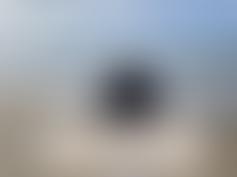 A woman walking on the beach towards the water.