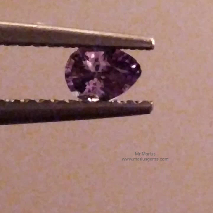 Thumbnail: purple alexandrite, picture in warm light, pear shaped cut.