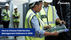 man and woman wearing high-vis jackets looking at computer server