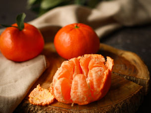 Fresh peeled and whole mandarins on a rustic slab