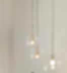 Three glowing glass pendant lights hanging from a bright white ceiling.