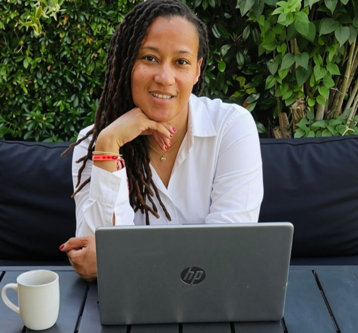 Coach assise devant son ordinateur dans un jardin