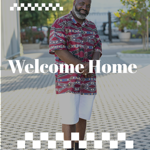 Man in patterned shirt stands with "Welcome Home" text overlay, smiling.