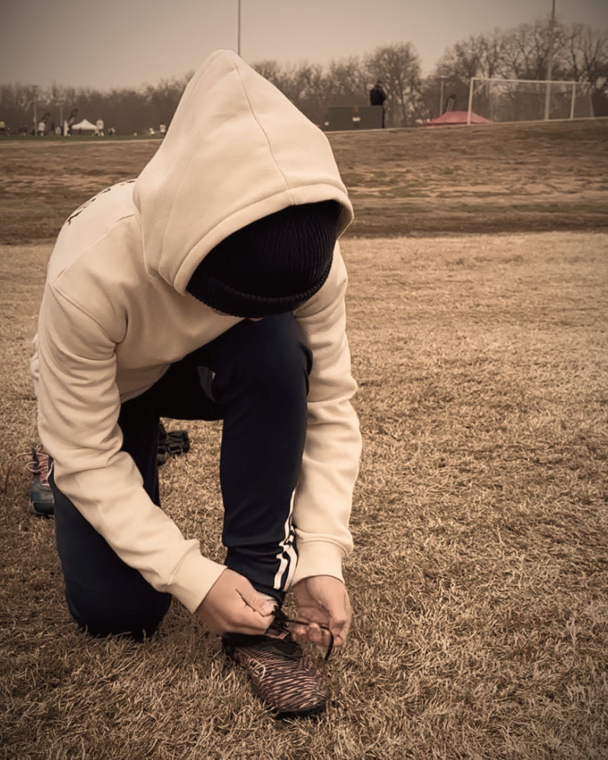Youth soccer player tying his shoes near the field during a tournament in a competitive environment
