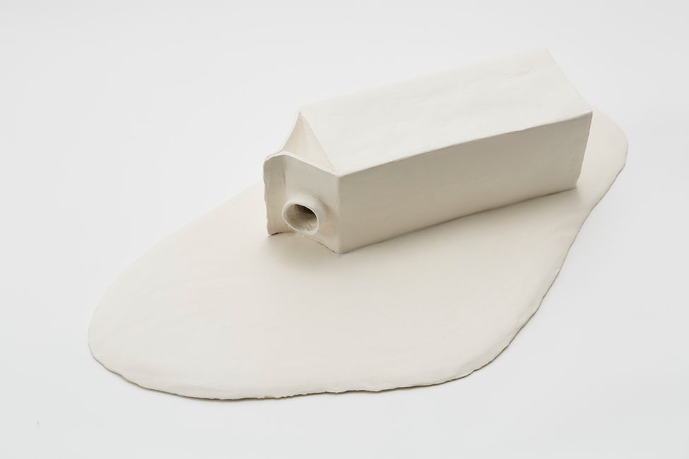 White ceramic milk carton lying down in a milk puddle on a white surface, studio shot. Lola Carlander Wade.