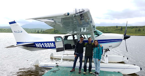 Guests pose for a photo in front of a floatplane at Caribou Lodge Alaska