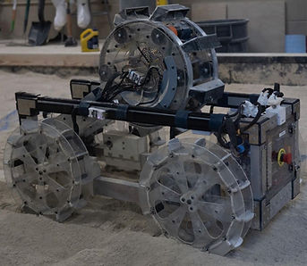 In addition to redesigning the excavation mechanism, we had to rethink the translation mechanism. As we learned from last year, linear actuators are extremely useful, but they take up a lot of space and are considerably heavy, therefore for this year we implemented a pivot point system, this allowed us to have a much larger range of motion, while also providing a much lower count of failure points. 

Nonetheless in order for the chassis to withstand such a high torque, it had to be reinvented. The objective was to distribute the concentrated moment as efficiently as possible through the entire chasis. In order to do that, we needed to decrease any loose connections, between the beams, that could wear and tear over time from the repetitive loading and potentially lead to failure, while also increasing the strength of the beam components that made up the chassis. In order to do so we decided to utilize aluminum box tube as the structural frame, for their high strength-weight ratio, and most importantly 3D printed closed fit connections between beams, that would hold tight each component an eliminate any type of insecure connections, while also providing us the capability of disassembling if needed, something welding did not provide. 