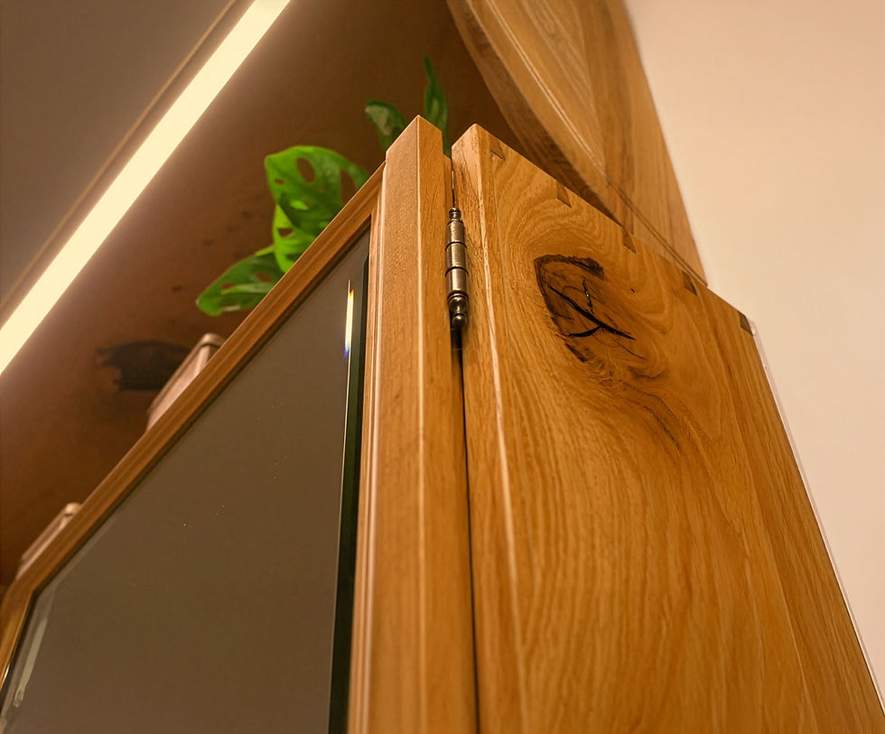 Detailný záber na remeselnú drevenú skrinku z masívu, s mosadzným pántom a presklenými dverami. Vidieť textúru dreva