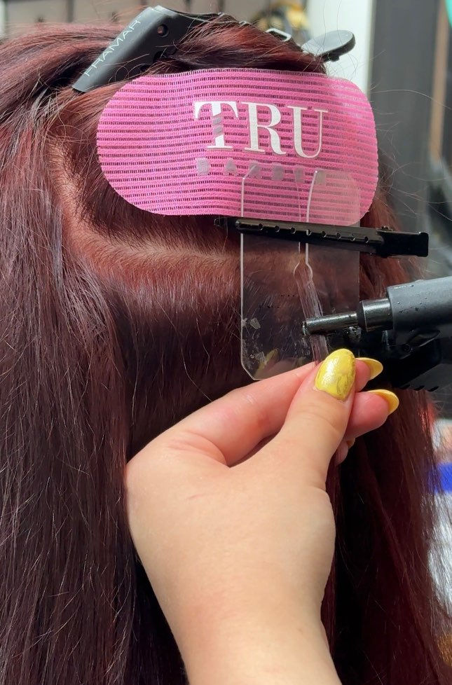 Close-up view of keratin tip extensions being applied to natural hair