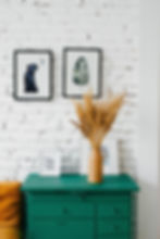 white brick wall, green sideboard with 2 watercolor prints on the wall- 1 jaguar looking at a moon, 1 a leaf.