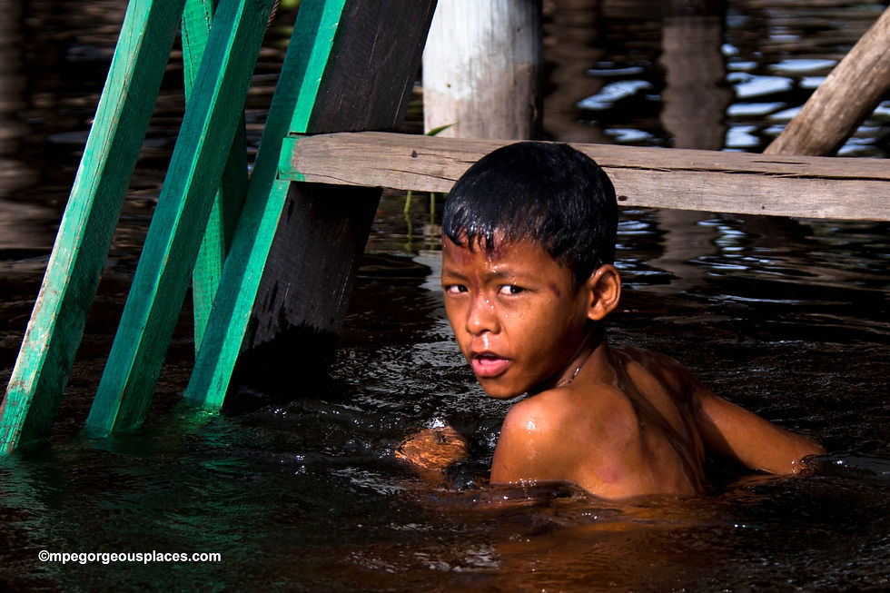 Childhood Joys: A young boy splashes in the refreshing waters beneath his home in Kampong Phluk's floating village