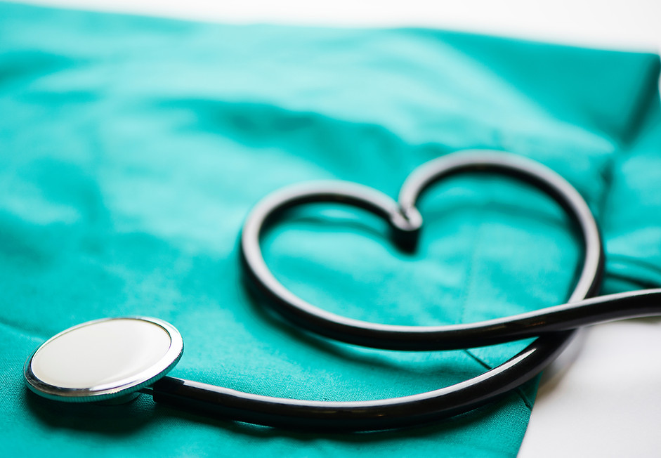 Stethoscope with the tubing in the shape of a heart sitting over scrubs