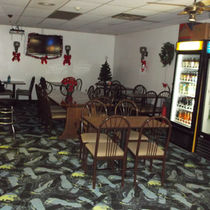 Interior view of a bowling alley with tables, chairs, and a cooler.