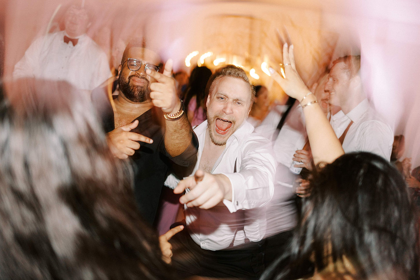 Invités dansant et levant les bras pendant une soirée de mariage photographiée au flash.
