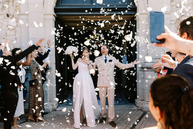 Mariés sortant de cérémonie sous des confettis devant leurs invités.