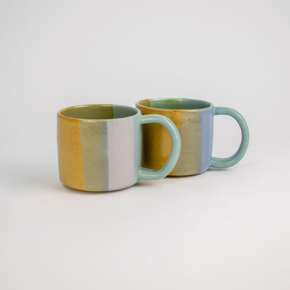 Two colorful ceramic mugs with vertical stripes and rounded handles.