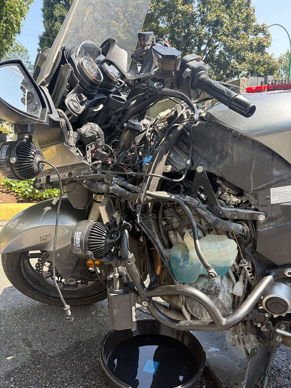 Yvan's Kawasaki Concours with the fairings stripped off in a parking lot, exposing the wiring and coolant reservoir during the radiator fan swap.