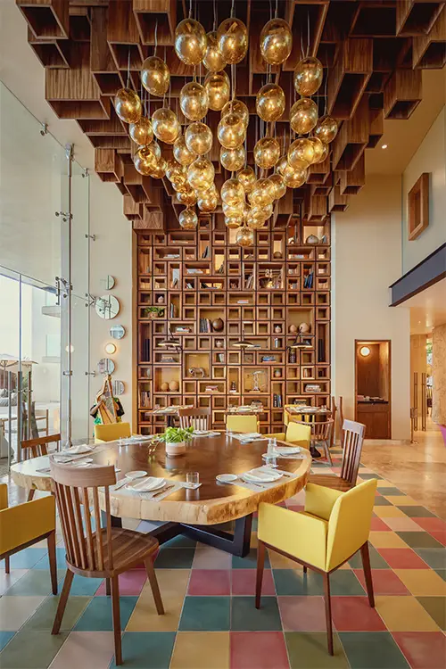 Signature restaurant interior at La Casa de la Playa with dramatic wood lattice ceiling, sculptural lighting, and vibrant design reflecting high-end Mexican artistry and culinary excellence.