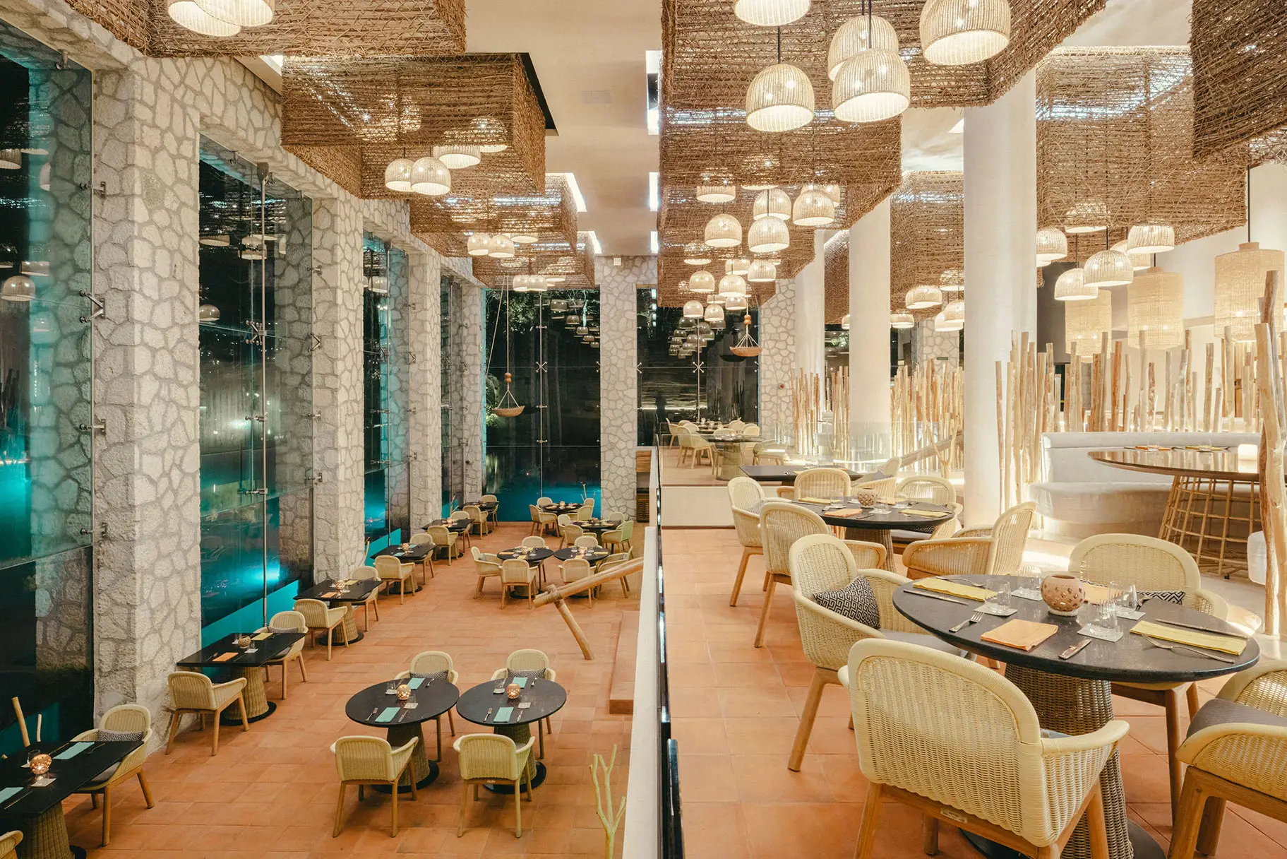 Multi-level fine dining restaurant with woven light fixtures and river views at Hotel Xcaret Arte, showcasing contemporary Mexican architecture, art-inspired design, and elevated adults-only dining experiences.