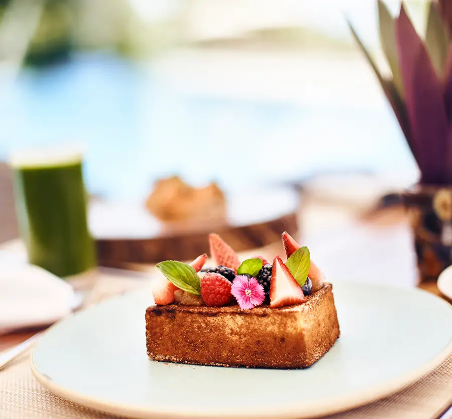Gourmet French toast topped with fresh berries and edible flowers at Hotel Xcaret, showcasing elevated dining, culinary artistry, and all-inclusive luxury resort cuisine in Riviera Maya.