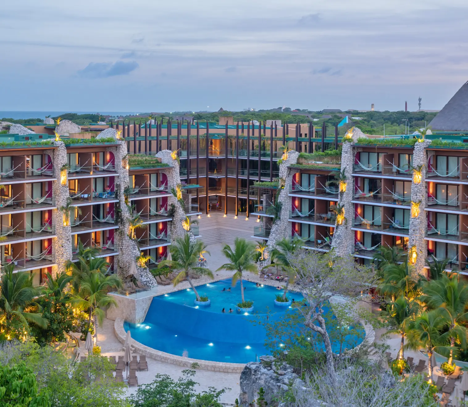 Hotel Xcaret Mexico courtyard with lagoon-style pool, hammock balconies, and eco-integrated architecture, showcasing family-friendly all-inclusive resort design and immersive Riviera Maya vacation experience