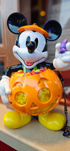Mickey Mouse holding a glowing jack-o’-lantern popcorn bucket during Mickey’s Not-So-Scary Halloween Party.