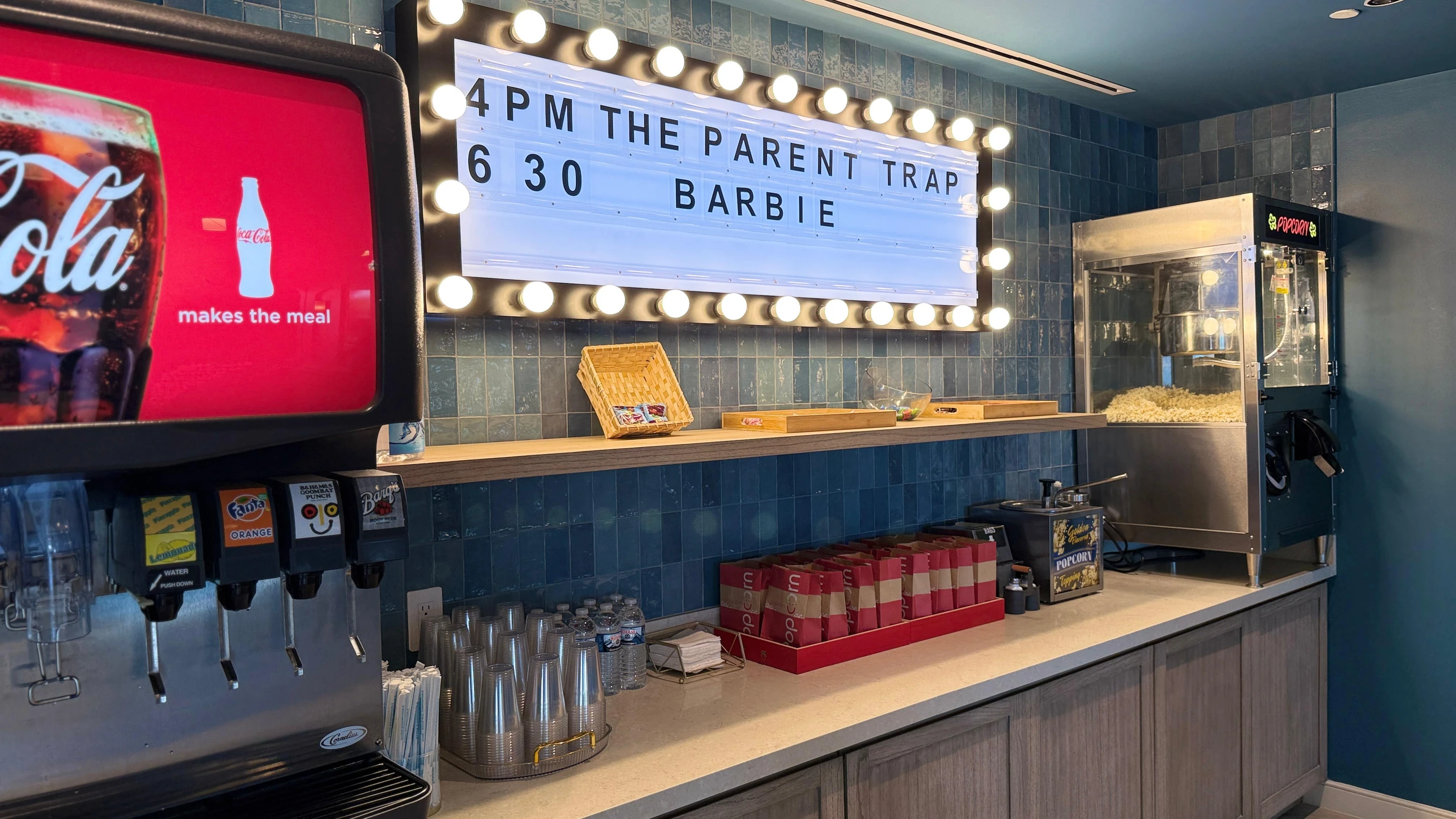 Beaches Turks & Caicos Starfish Cinema snack bar featuring popcorn machine, soda fountain, and movie schedule board, highlighting family-friendly entertainment and all-inclusive resort amenities in the Caribbean.