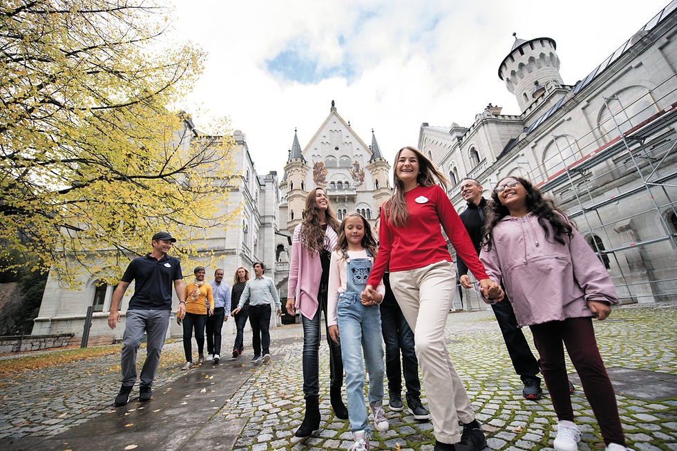 Adventure by Disney group walking together through a historic European castle courtyard, led by a Disney-trained Adventure Guide and surrounded by families exploring cobblestone paths and iconic architecture. Image highlights the Disney Difference with Adventures by Disney, showcasing expertly guided storytelling, seamless logistics, and immersive cultural experiences designed for families. Curated by Brandi Parker, Certified Disney Destinations Specialist, specializing in Adventure by Disney vacations and thoughtfully planned Disney-guided travel experiences.